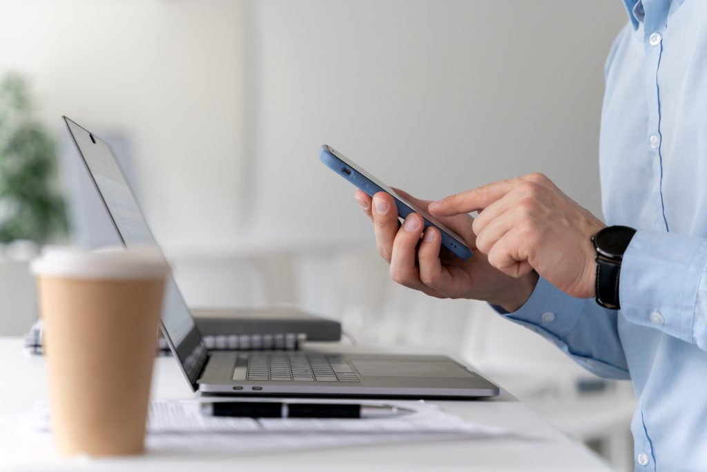 Man with phone by laptop